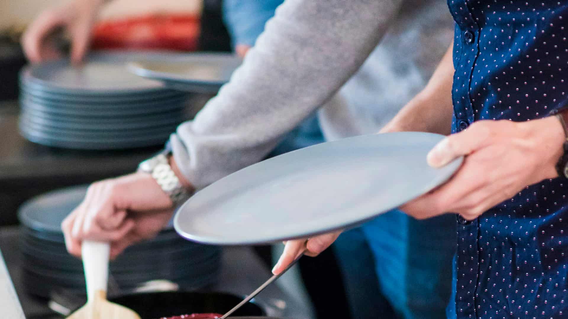 Hands passing plates above a stack of plates