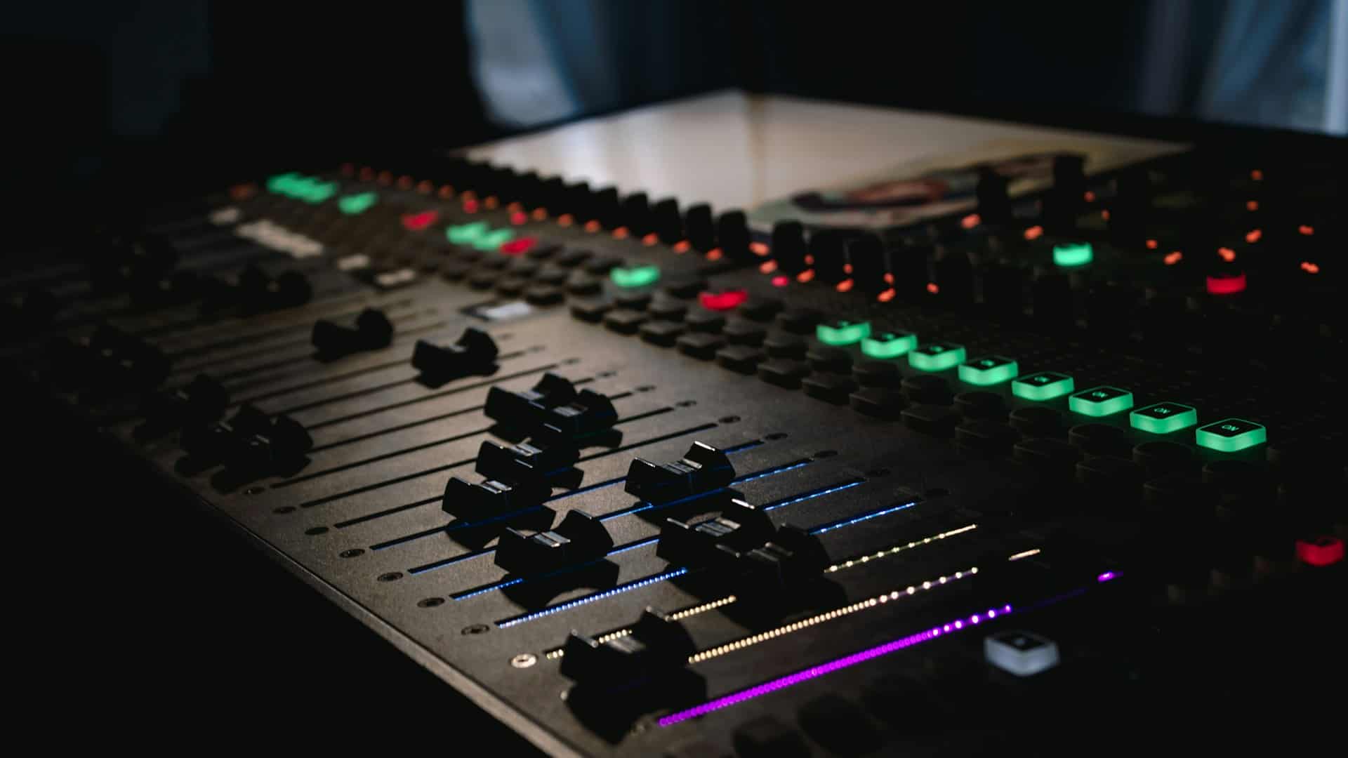 A digital mixing console, its controls lit in the dark