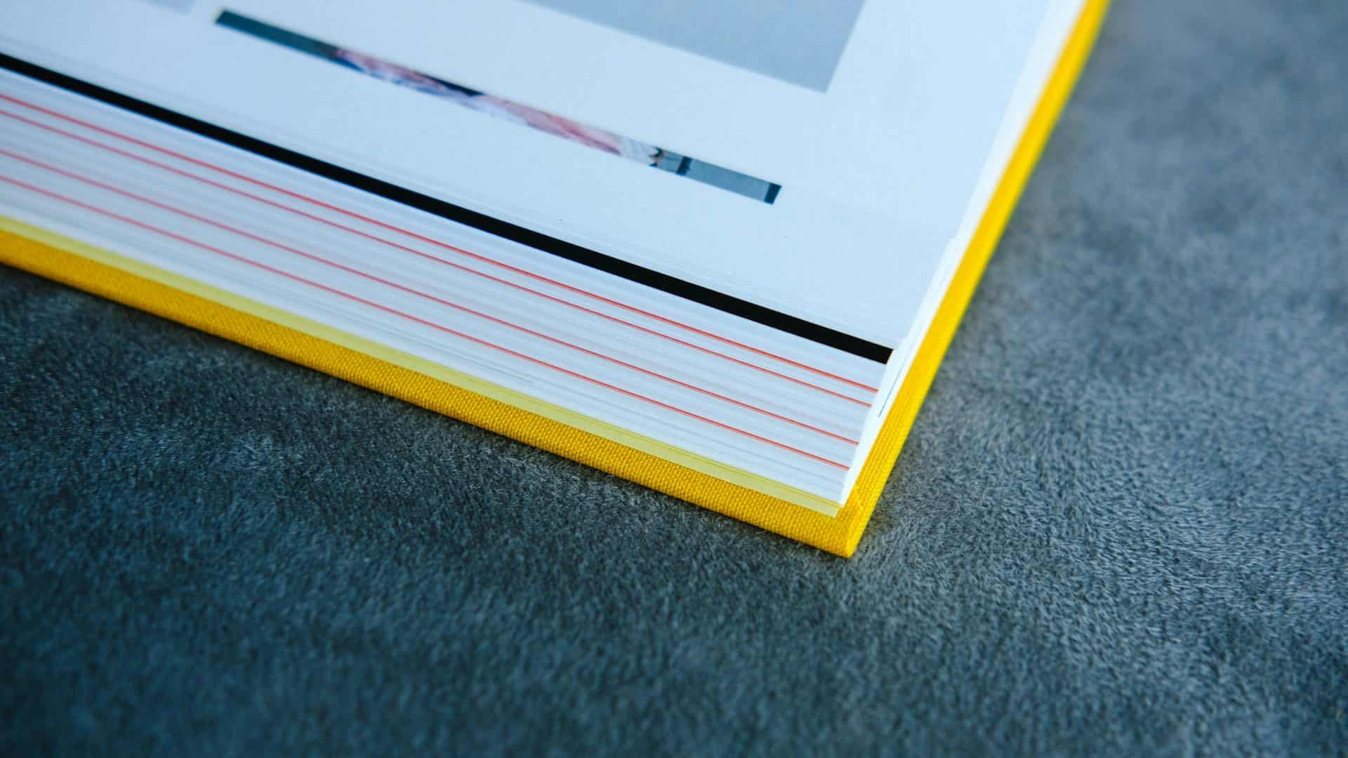 A photo album with a yellow cover resting on grey cloth