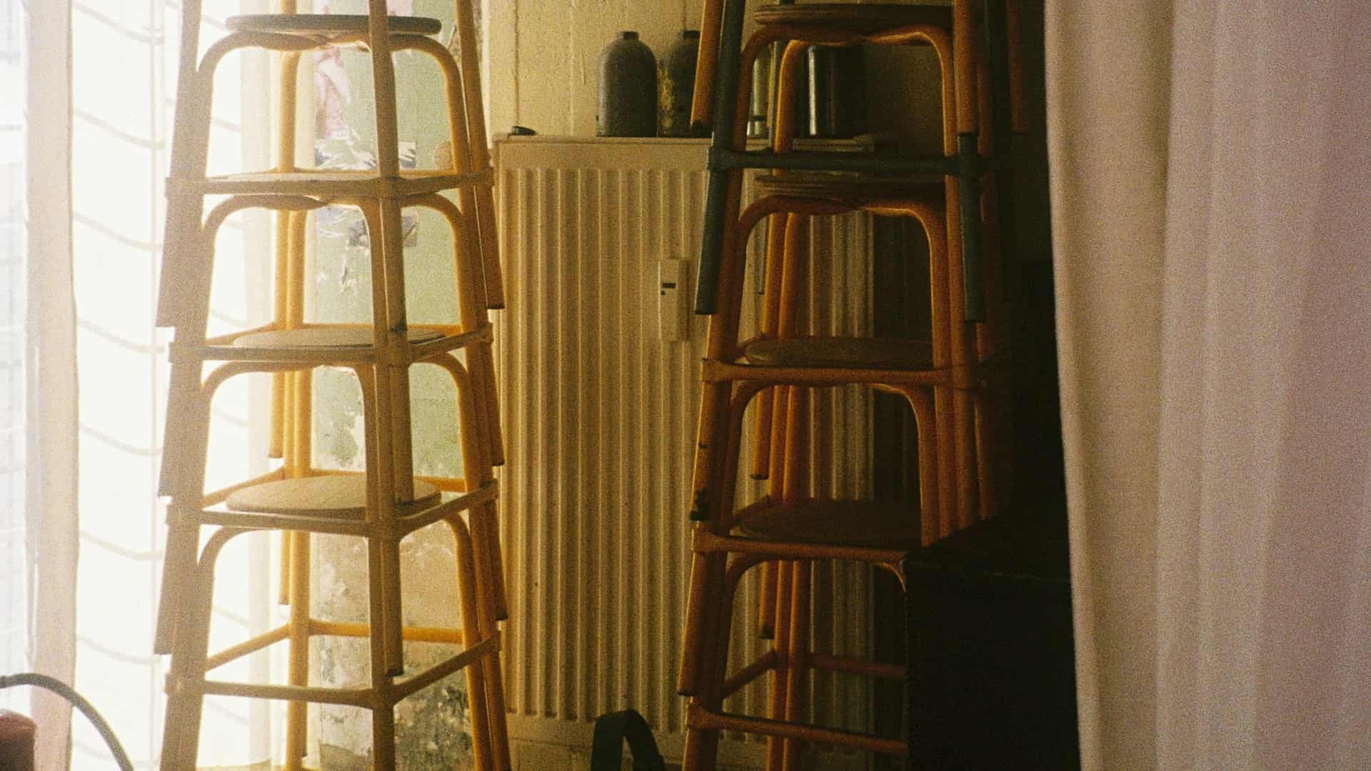 Two stacks of rattan stools tidied away near a window