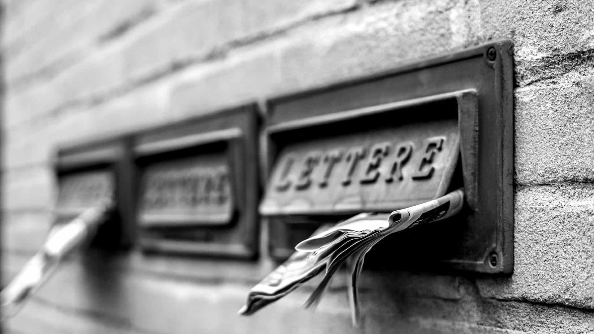 Three stone letterboxes, mail sticking out of one of them